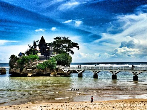 Pemandangan ikonik Pura Amarta Jati di atas pulau karang Pantai Balekambang, Malang, yang terhubung dengan jembatan panjang.