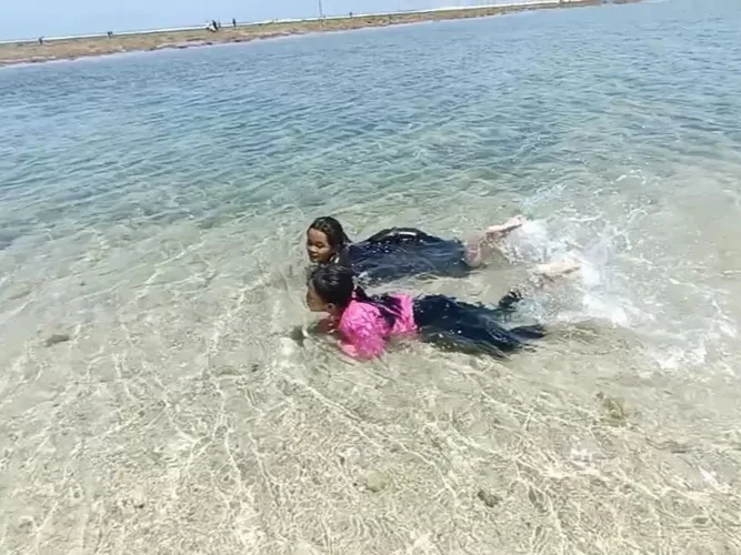 Dua orang anak sedang berenang di pantai balekambang, air yang jernih dan ombak kecil membuat aktifitas berenang semakin menyenangkan.