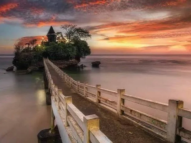 Siluet magis Pura Amarta Jati di Pantai Balekambang saat momen matahari terbenam (sunset) yang memukau.